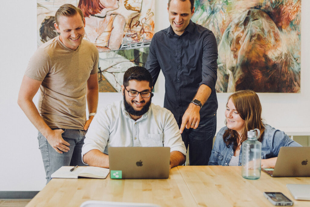 Group of four looking at a laptop together